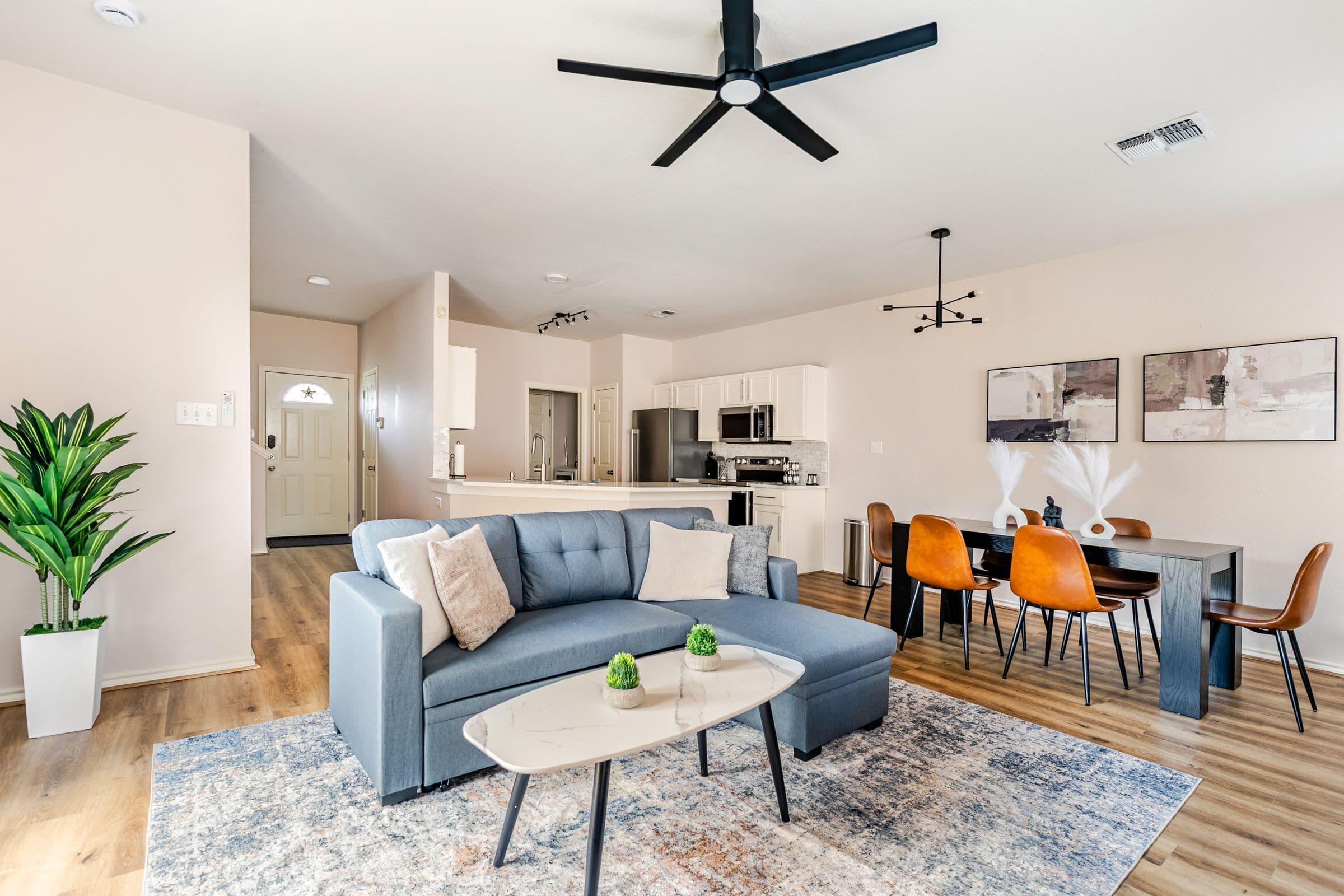 Open-plan living room with a sectional sofa, the dining table, and the kitchen beyond