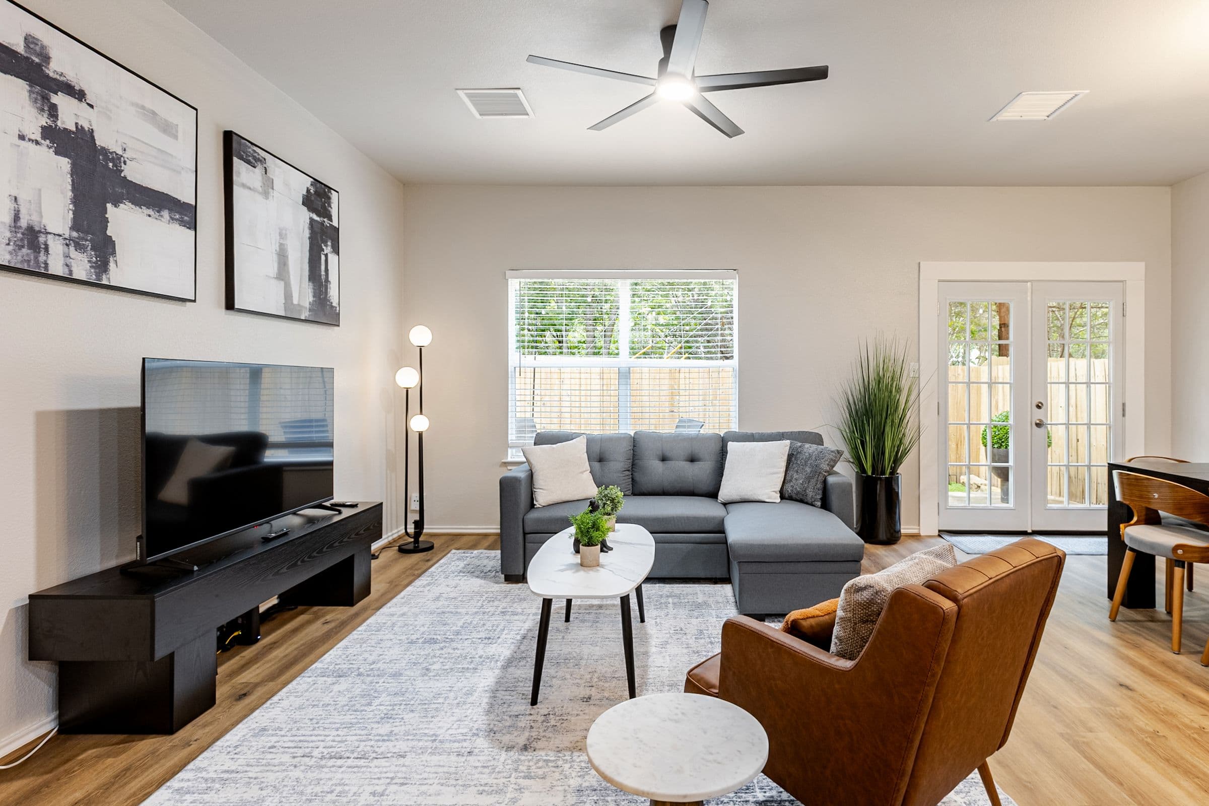 Living room with a sectional sofa and TV, French doors out to the fenced back yard